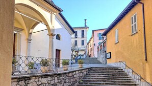A stone staircase leading up to a building with a white facade and a yellow building on the right.