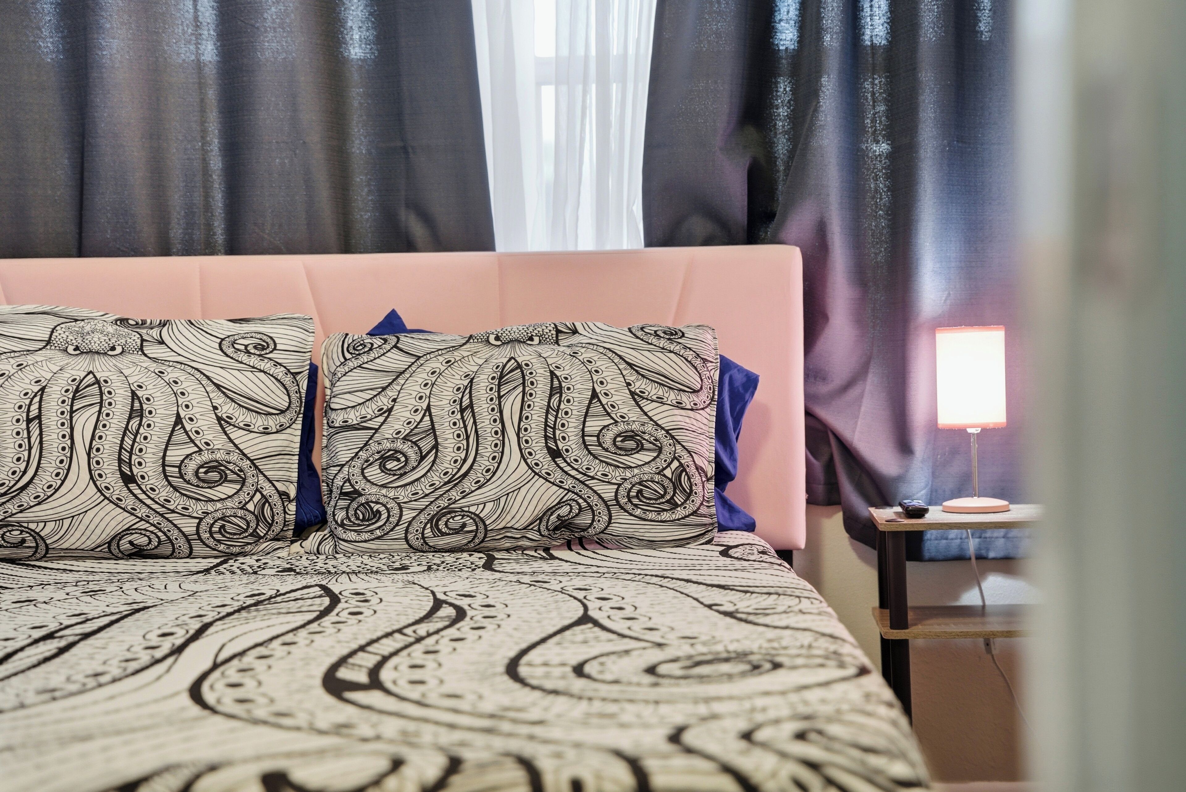 Een bed met beddengoed met een patroon en een nachtkastje met een lamp.