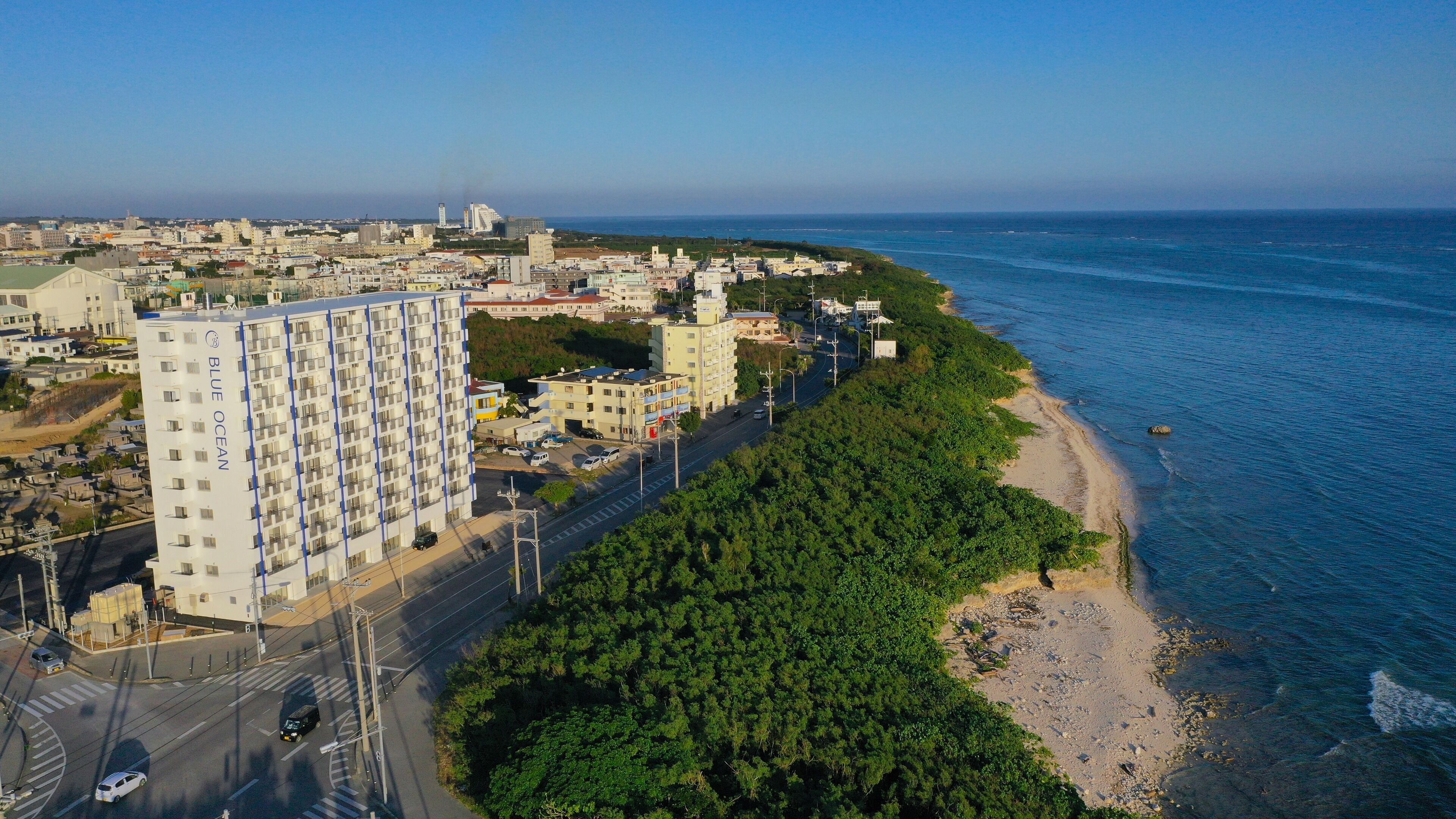 A coastal cityscape with a prominent multi-story building labeled "BLUE OCEAN" adjacent to a beach.