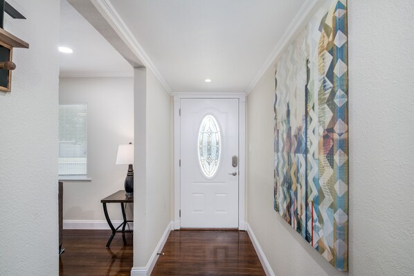 Un couloir avec une porte blanche, un mur à motifs et un plancher en bois.