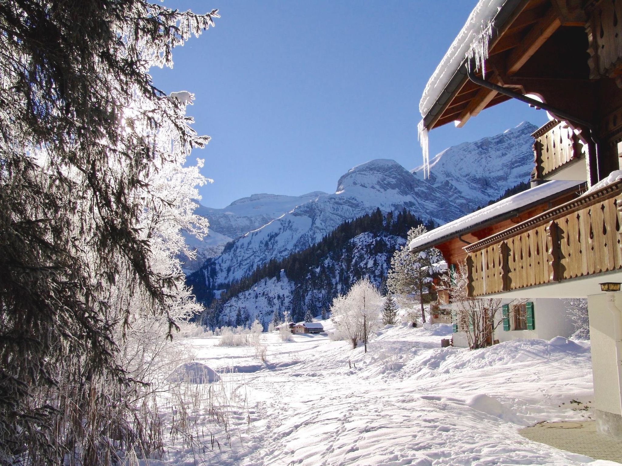 Eine verschneite Berglandschaft mit einem Holzhaus in traditioneller Bauweise.