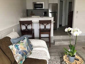 Un salon comprenant un canapé, deux fauteuils, une table basse et un pot d’orchidée.