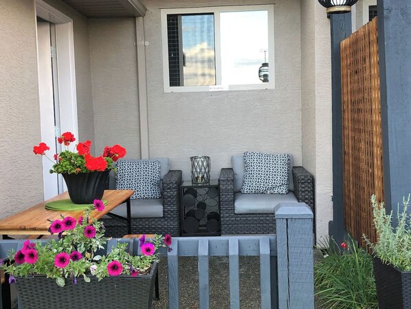 A patio with outdoor furniture, a small table, and potted plants.