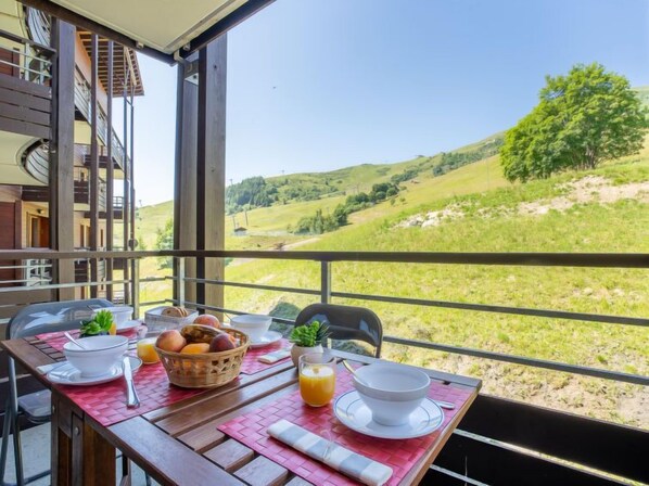 A dining table with breakfast items and a scenic view of a hilly landscape.