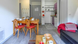 Um espaço compacto com área de refeições, cozinha compacta e sofá.
