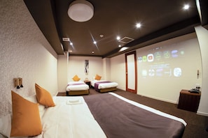 A hotel room with two beds, a projection screen displaying room amenities, and a wooden nightstand.