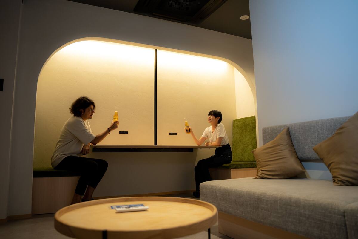 Two people sitting on a bench in a modern room with a sofa and a small table.