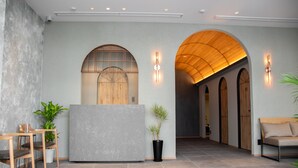 A modern reception area with a reception desk, seating, and arched wooden doorways. - Hotel S-presso South (Osaka)
