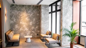 A modern lounge area with a sofa, two armchairs, a small table, and a potted plant. - Hotel S-presso South (Osaka)