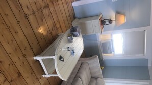 A room with a wooden floor, a gray sofa, a white table, and a lamp.
