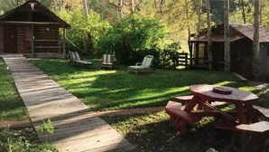A wooden deck leading to a grassy area with a picnic table and two chairs. - Moonlight Cottage “Hoot”, sleeps 5 (Rigby)