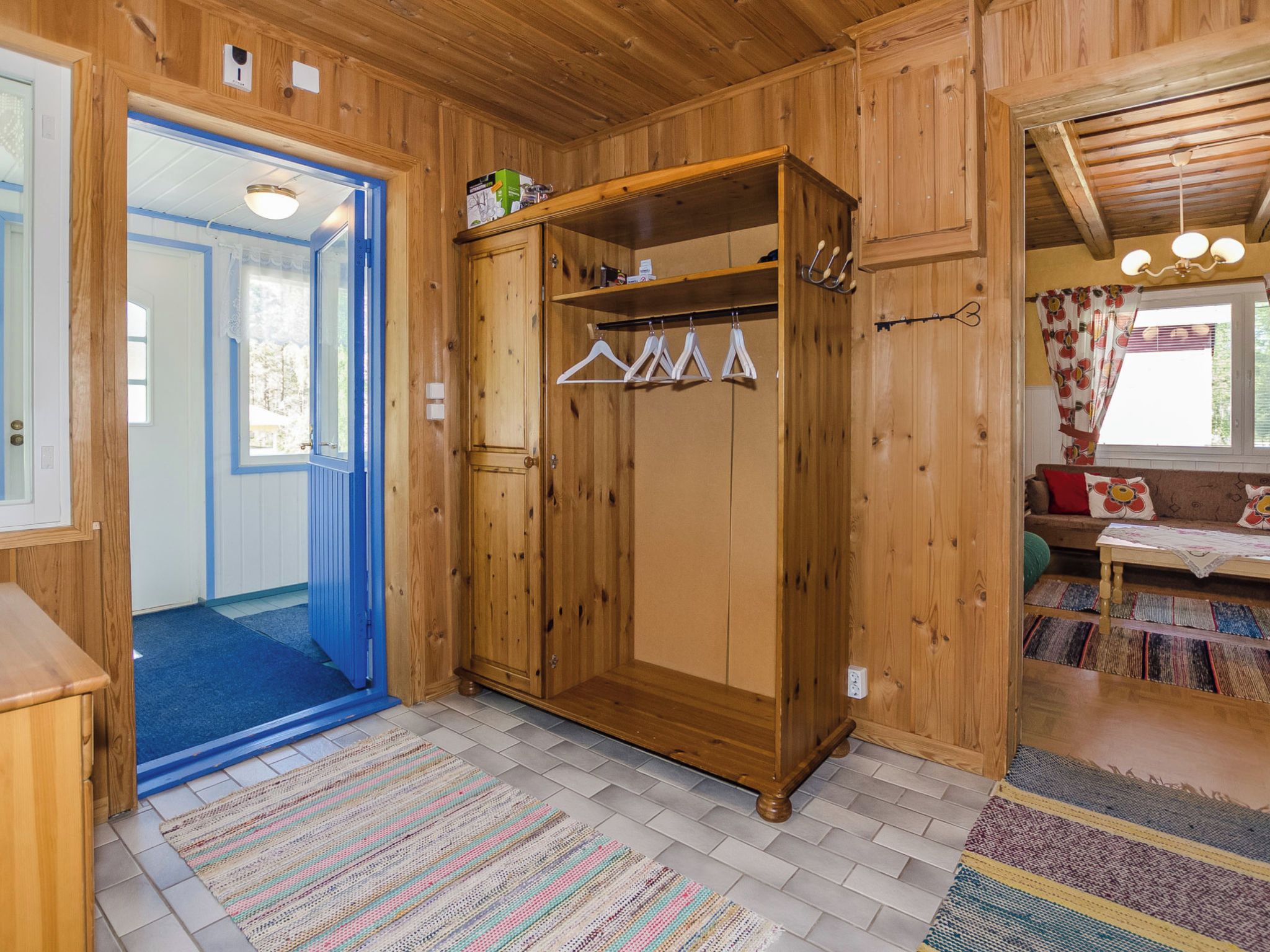 Um quarto de madeira com um guarda-roupa, uma porta azul e um tapete estampado.