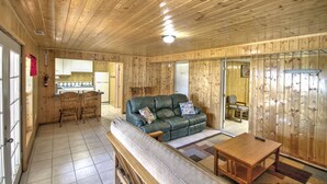 A wooden interior with a sofa, chairs, a table, and a kitchen area.
