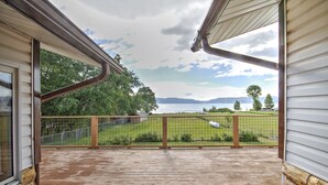 A wooden deck with a view of a grassy area and mountains in the distance.