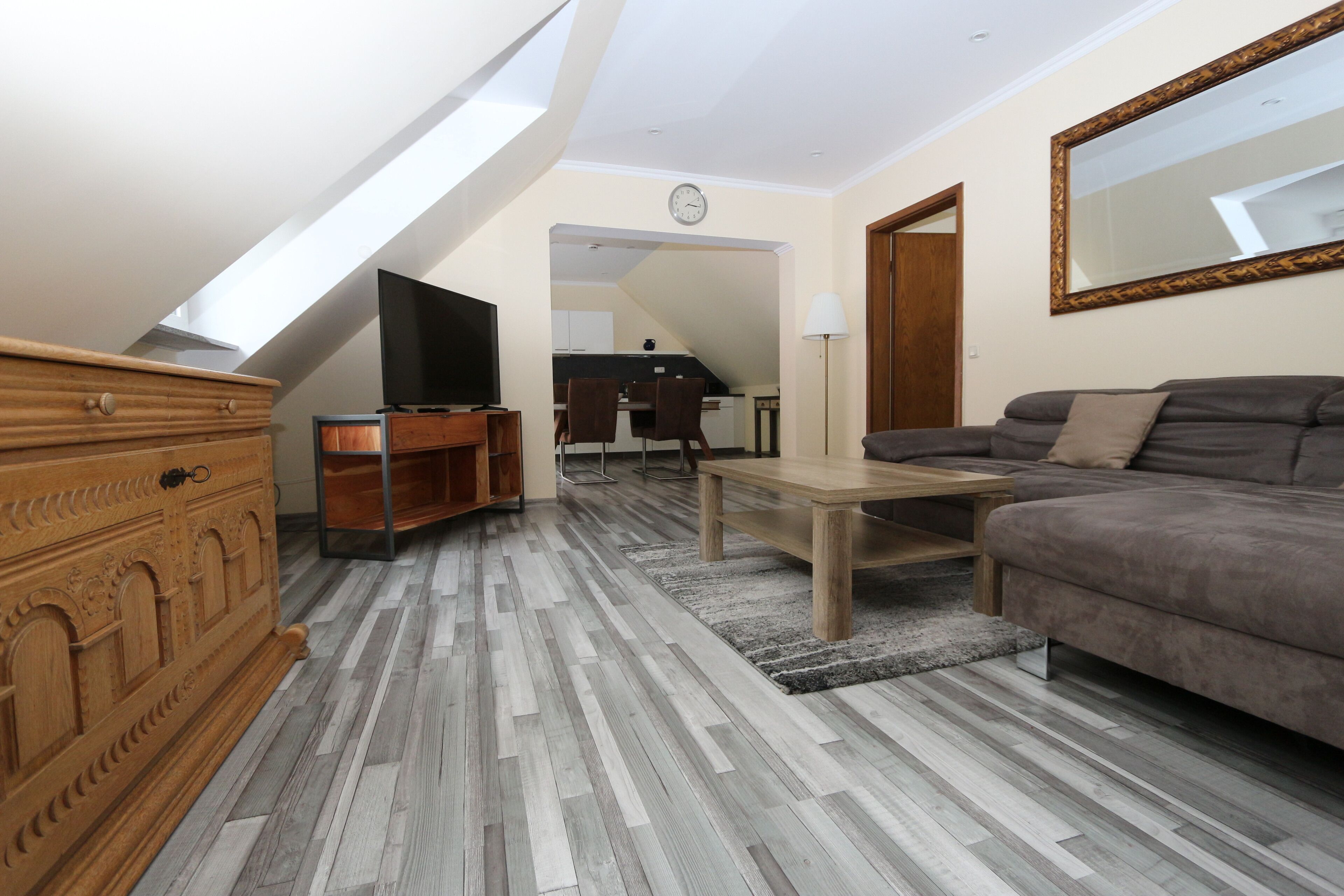 Un salon moderne avec un plafond de style industriel, un canapé, un téléviseur et une commode en bois.