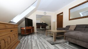 Uma sala de estar moderna com teto estilo loft, um sofá, uma TV e um aparador de madeira.