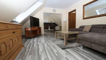 Un salon moderne avec un plafond de style industriel, un canapé, un téléviseur et une commode en bois.