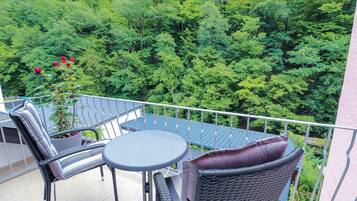 Un balcon agrémenté d’une table et de chaises, entouré d’une végétation luxuriante.