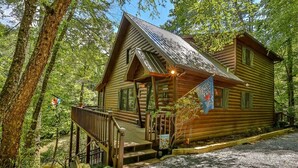 A log cabin with a porch, steps, and a flag.