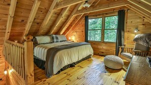 A wooden cabin bedroom with a bed, a chair, a table, and a window. - The Mason Jar At Cherry Log | Cherry Log, GA (Cherry Log)