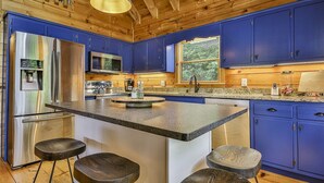A modern kitchen with blue cabinets, stainless steel appliances, and a central island with stools. - The Mason Jar At Cherry Log | Cherry Log, GA (Cherry Log)