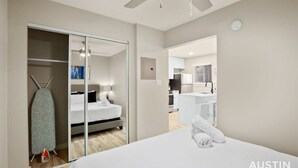 Ett modernt hotellrum med en säng, en garderob och ett litet kök.
