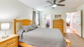 A bedroom with a bed, nightstands, a dresser, a ceiling fan, and a door leading to another room. - Watts Bar Lake Escape: Private Boat Dock + Ramp! (Spring City)
