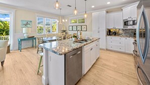 A modern kitchen with white cabinets, a granite countertop, and stainless steel appliances.