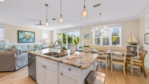 A spacious kitchen with a large island, white cabinetry, and pendant lighting.