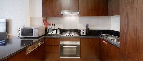 A modern kitchen with wooden cabinets, a built-in microwave, a gas stove, and a stainless steel sink.