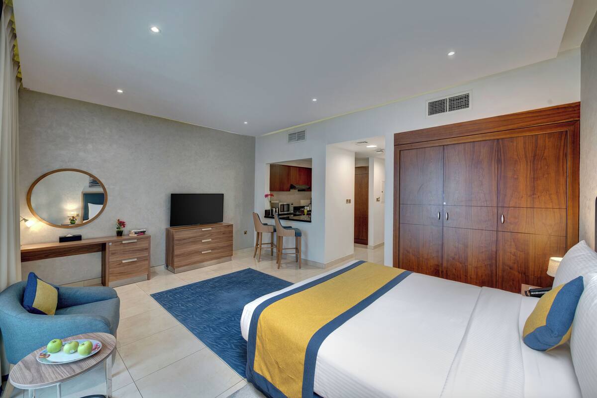 Una habitación de hotel moderna con una cama grande, un escritorio, un televisor y un armario.