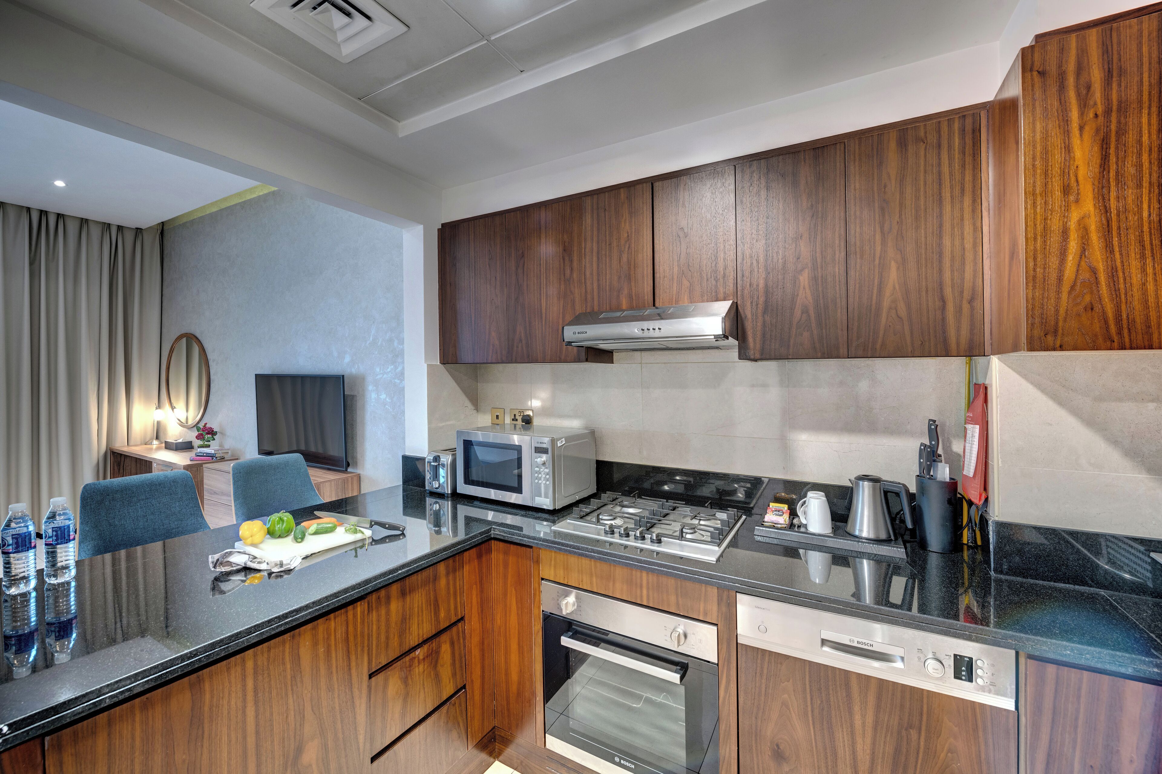 A modern kitchen with wooden cabinets, a stainless steel range, a microwave, and a built-in oven.