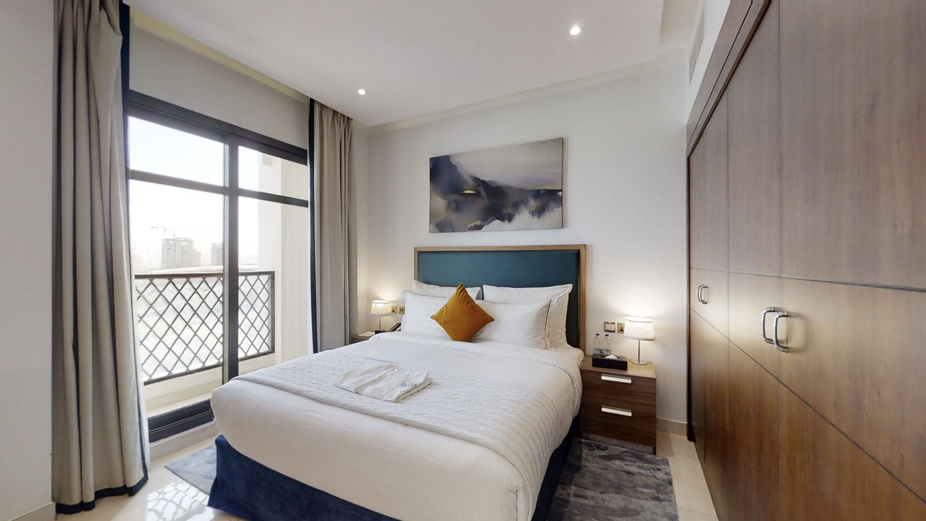 A hotel room with a large bed, a view of the city, and a wardrobe.