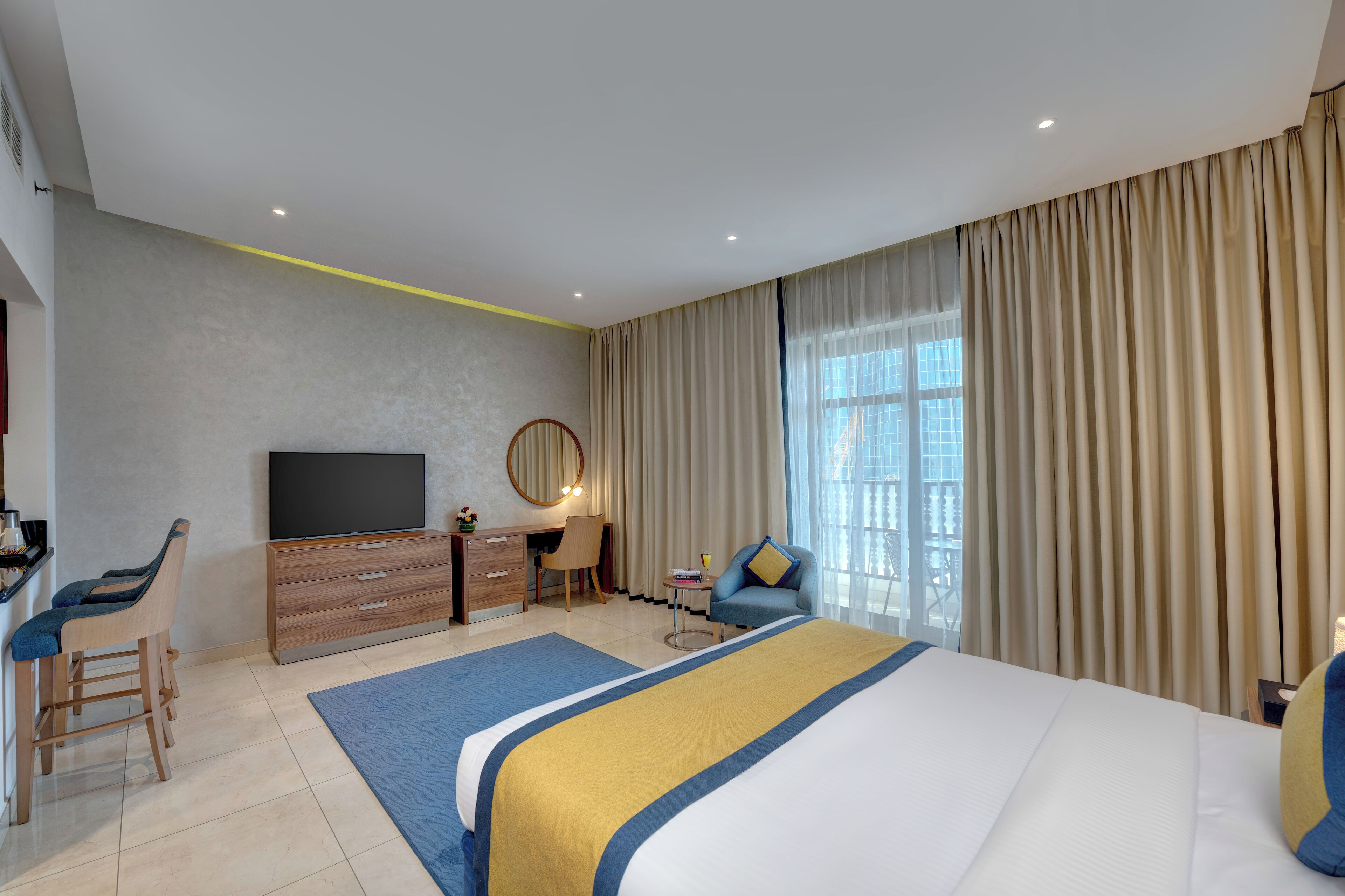 Una camera d'albergo moderna con un letto grande, una scrivania con una sedia, una televisione e vista sulla città.