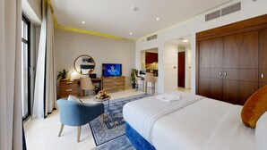 Una habitación de hotel moderna con una cama grande, un escritorio con computadora, un televisor y un armario.