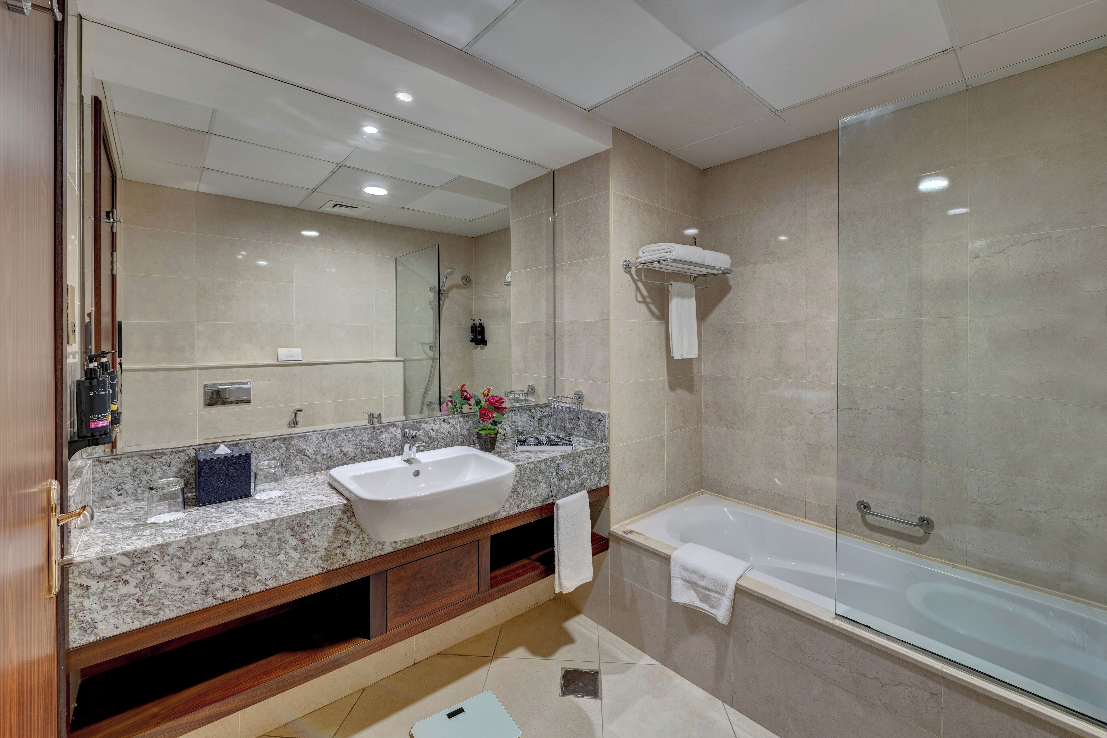 Un baño moderno con lavamanos de mármol, ducha con mampara de vidrio y bañera.