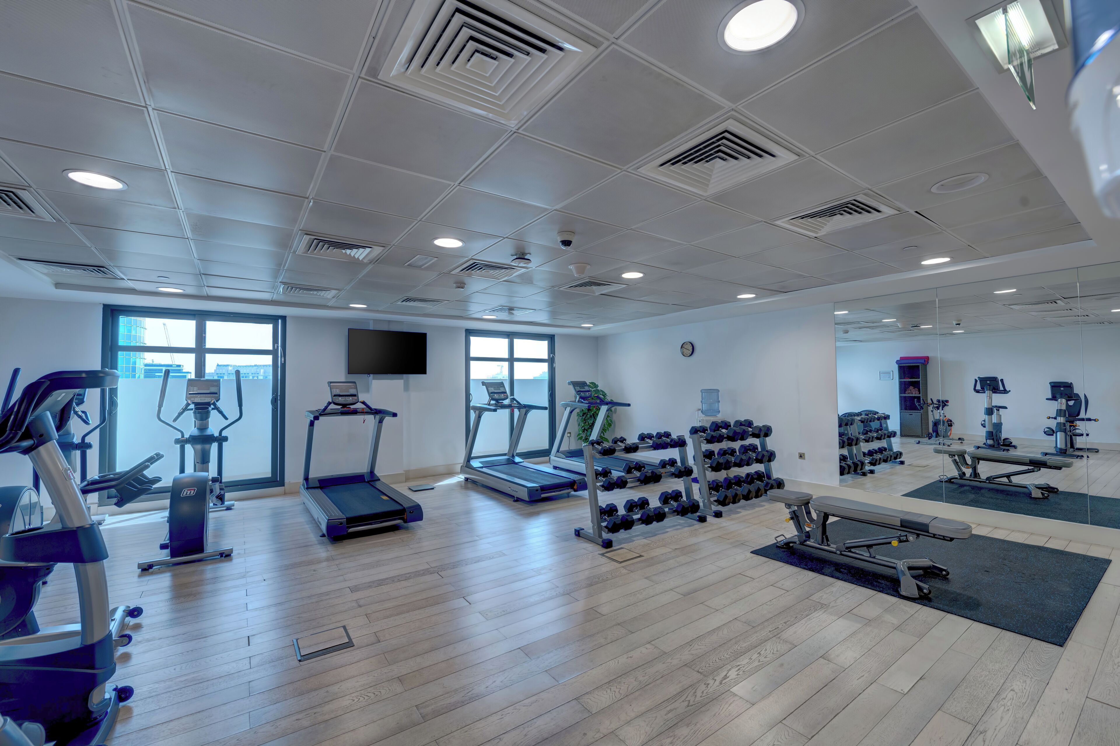 Une salle de sport équipée de tapis de course, de vélos elliptiques et de poids libres.