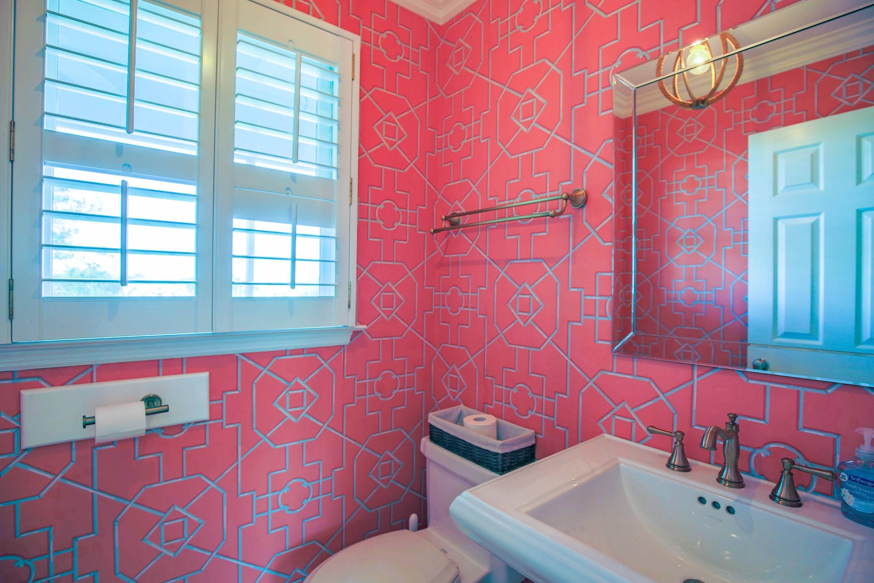 A bathroom with a pink patterned wall, a white sink, and a toilet.