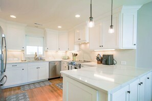 A modern kitchen with white cabinetry, a central island, and pendant lighting.