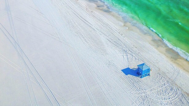 A beach with clear turquoise water, a sandy shore, and a few beach umbrellas. - Near Siesta Key - single story pet friendly (Sarasota)