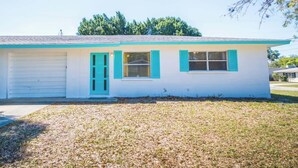 A single-story house with a garage, a front porch, and a small front yard. - Near Siesta Key - single story pet friendly (Sarasota)