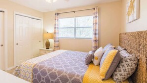 A bedroom with a bed, curtains, a ceiling fan, and a window. - Near Siesta Key - single story pet friendly (Sarasota)