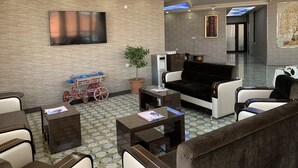 A modern lobby with a flat-screen TV, a potted plant, a vintage bicycle, and a sofa.