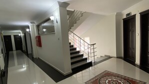 A spacious hallway with a polished floor, a staircase with a metal railing, and a decorative rug.