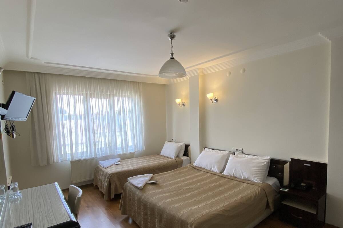 Una habitación de hotel con dos camas, un escritorio y una ventana con cortinas.