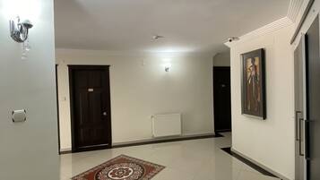 A spacious hallway with a patterned rug, a radiator, and a framed picture on the wall.