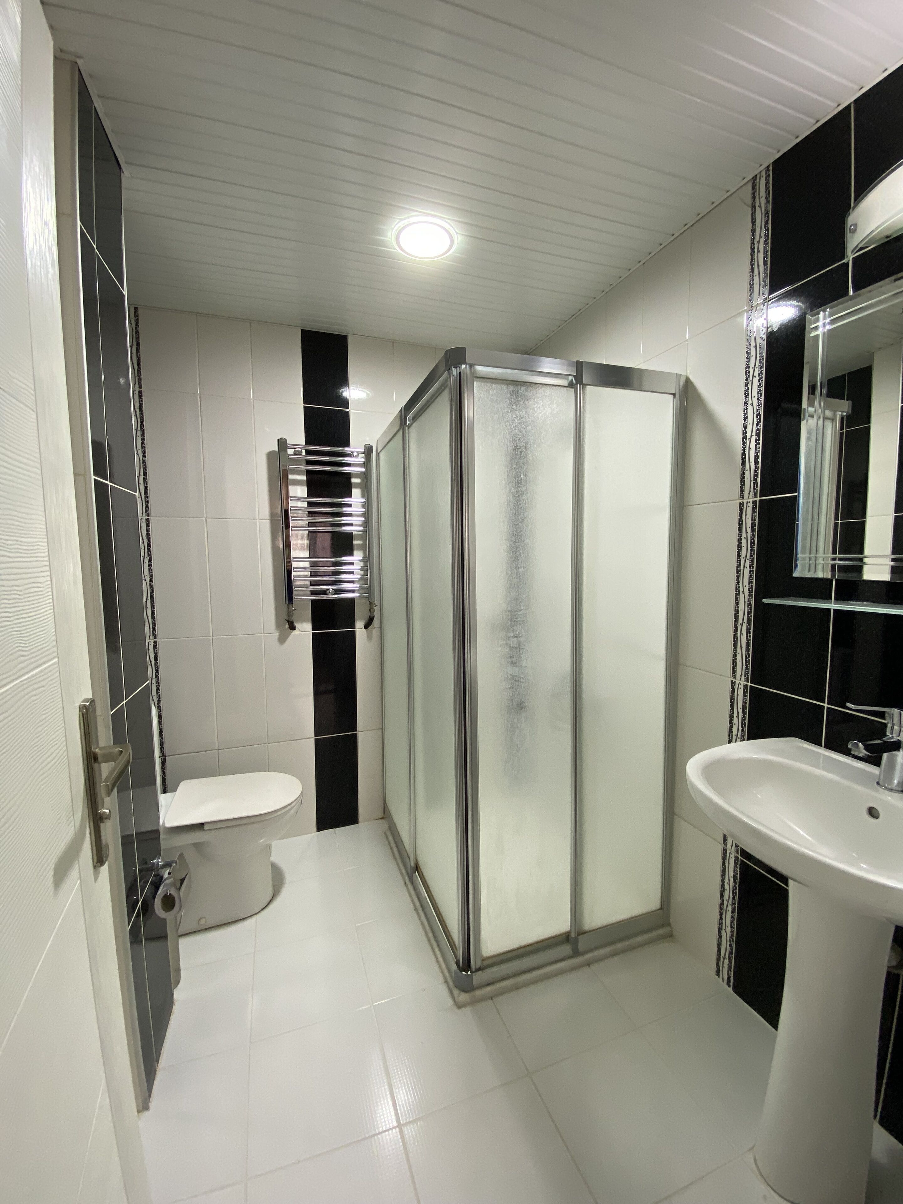 A bathroom with a glass-enclosed shower, a toilet, and a sink.