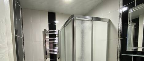 A bathroom with a glass-enclosed shower, a toilet, and a sink.