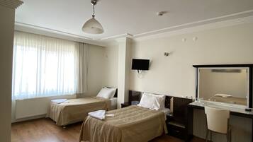 A hotel room with two beds, a desk, a chair, a large mirror, and a window with curtains.