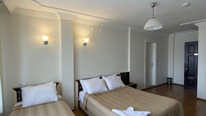 A hotel room with two beds, wooden flooring, and a white ceiling.